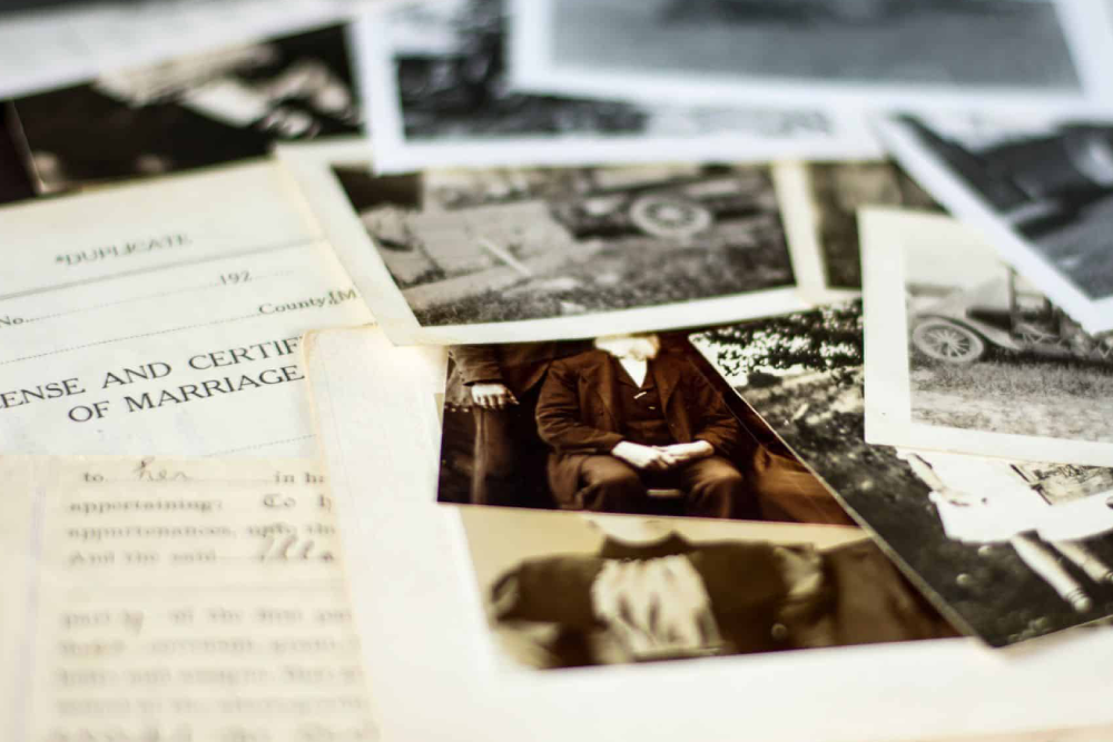 A marriage certificate beside old family photographs, in soft focus